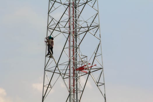 Painting cell phone antennas and the internet to enhance beauty by young hard-bodied laborers with audacity to reach heights is a dangerous job. photo