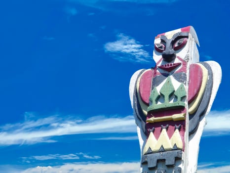 A totem wood pole in the blue cloudy background photo