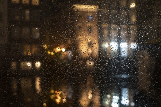 Rain drops on glass window at night photo