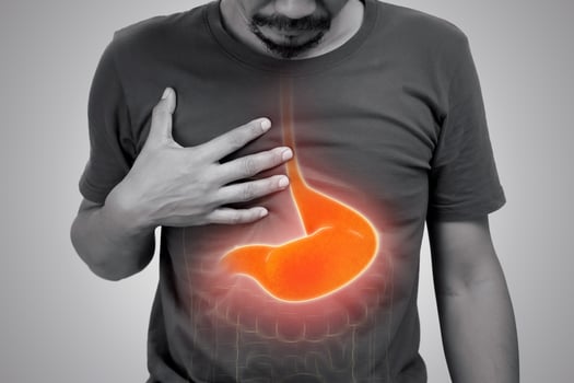 Asian man suffering from gastritis on gray background. photo