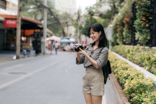 Young Asian woman backpack traveler using digital compact camera, enjoying street cultural local place and smile. Traveler checking out side streets. photo