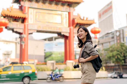 Young Asian woman backpack traveler enjoying China town street food market in Bangkok, Thailand. Traveler checking out side streets. photo