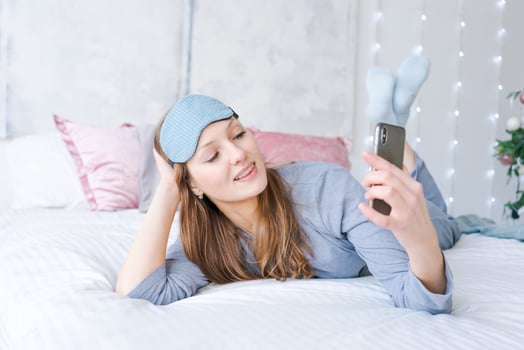 Young woman with blue sleep mask with charming smile Looking at phone camera photo