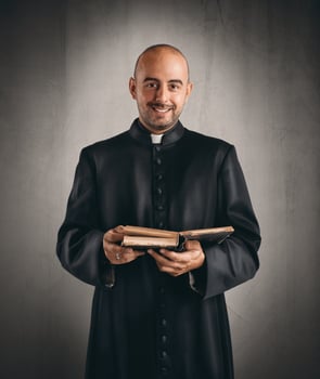 Priest smiling and holding a bible photo