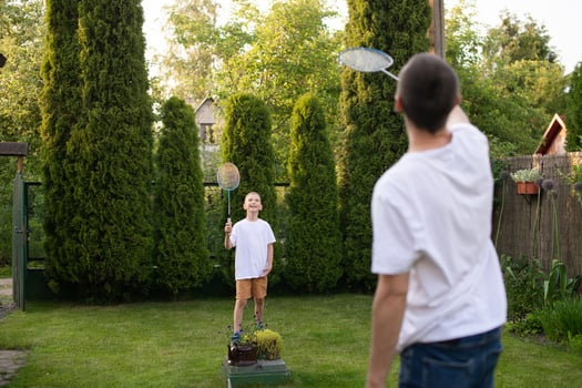 Cheerful dad outside playing badminton with his son in a white T-shirt photo