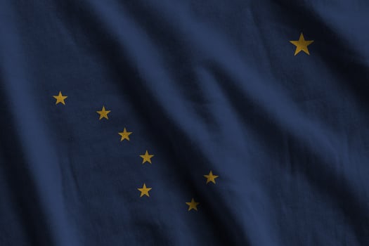 Alaska US state flag with big folds waving close up under the studio light indoors. The official symbols and colors in banner photo