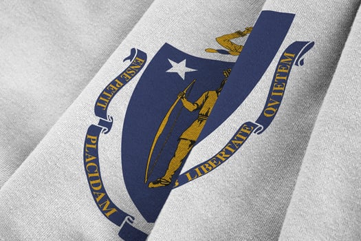 Massachusetts US state flag with big folds waving close up under the studio light indoors. The official symbols and colors in banner photo