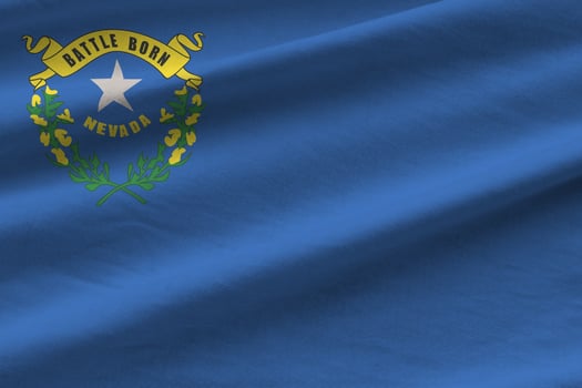 Nevada US state flag with big folds waving close up under the studio light indoors. The official symbols and colors in banner photo