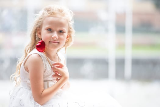 Little girl holding a small red heart. Child with a toy heart. photo