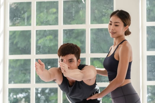 Asian female instructor teaching yoga to student in the class photo