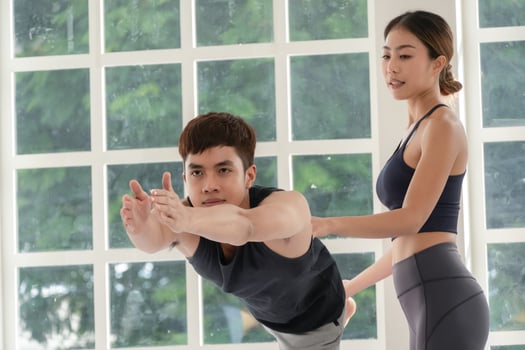 Asian female instructor teaching yoga to student in the class photo