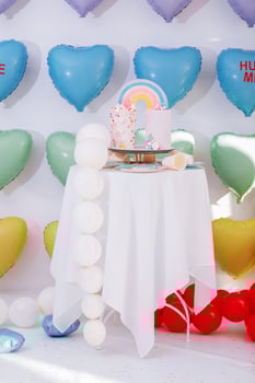 big Birthday cake with rainbow, colorful Sprinkles. on many colorful heart balloons background. birthday party. sweet holiday. photo