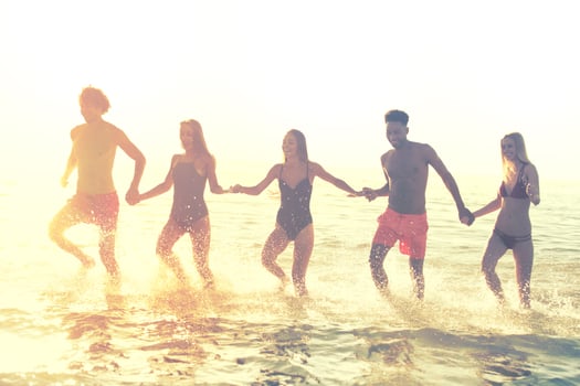 Group of friends run in the sea. Concept of summertime photo
