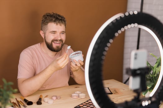 Famous blogger. Cheerful male vlogger showing cosmetics products while recording video and giving advices for his beauty blog. Make-up artist and recording beauty vlog concept photo