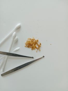 Earwax and two ear pick tools and cotton swabs On the light blue table top photo