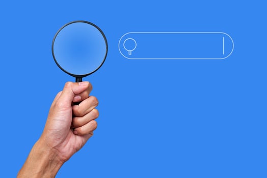 Hand holding a magnifying glass and search symbols photo