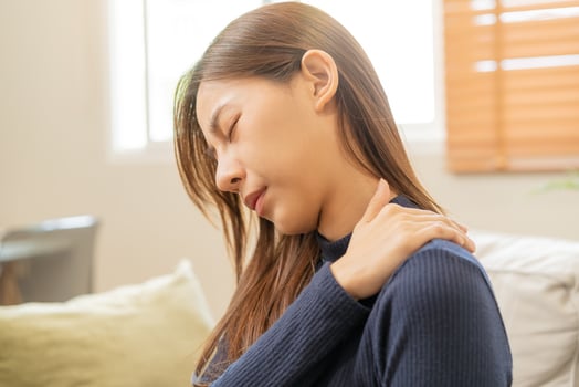 Body muscles stiff problem, asian young attractive woman, girl pain with back pain ache from work, holding massaging rubbing shoulder hurt or sore, painful sitting on sofa at home. Healthcare people. photo