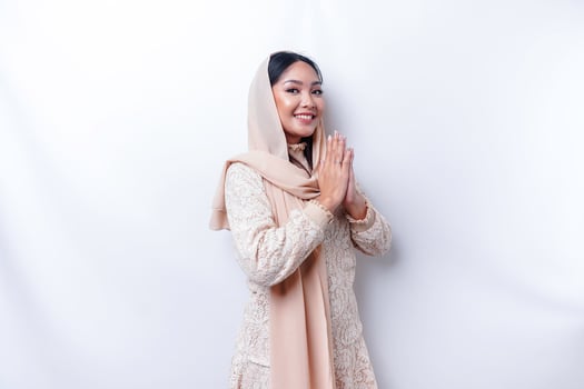 Portrait of a young beautiful Asian Muslim woman wearing a hijab gesturing Eid Mubarak greeting photo