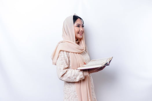 Young Asian Muslim woman smiling and holding the Quran photo