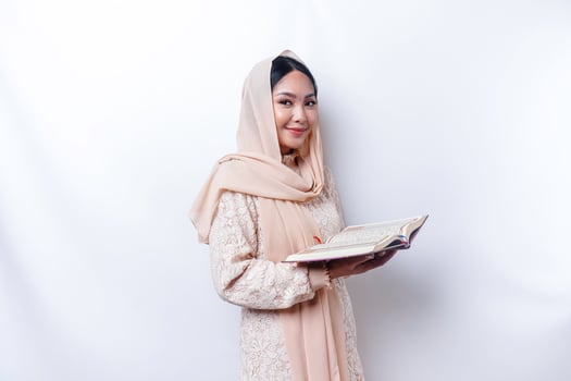Young Asian Muslim woman smiling and holding the Quran photo