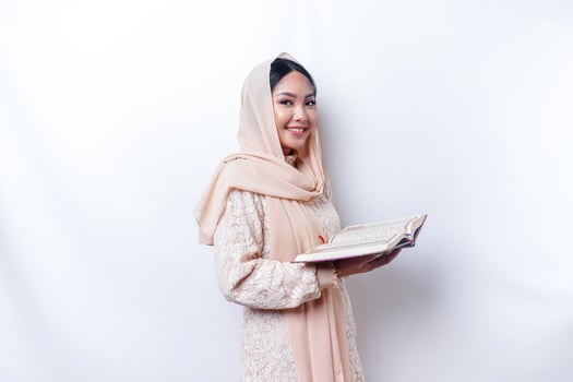 Young Asian Muslim woman smiling and holding the Quran photo