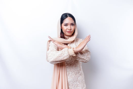 Beautiful Asian Muslim woman wearing a hijab with hand gesture pose rejection or prohibition with copy space photo
