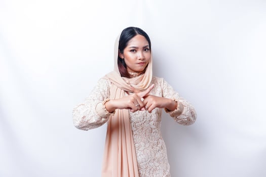 Beautiful Asian Muslim woman wearing a hijab with hand gesture pose rejection or prohibition with copy space photo