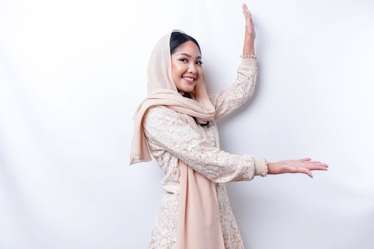 Young Asian Muslim woman smiling while pointing to copy space beside her photo