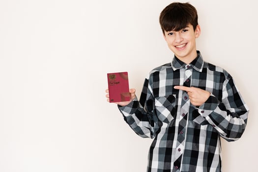 Young teenager boy holding Portugal passport looking positive and happy standing and smiling with a confident smile against white background. photo