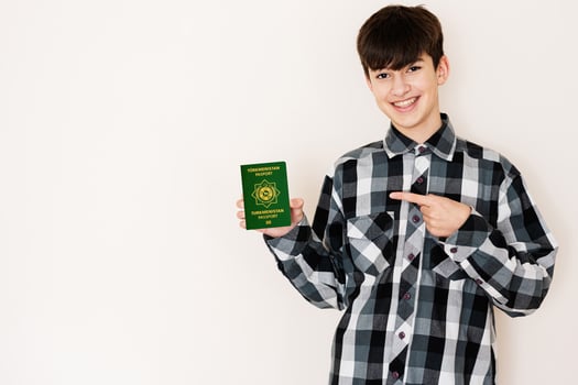 Young teenager boy holding Turkmenistan passport looking positive and happy standing and smiling with a confident smile against white background. photo