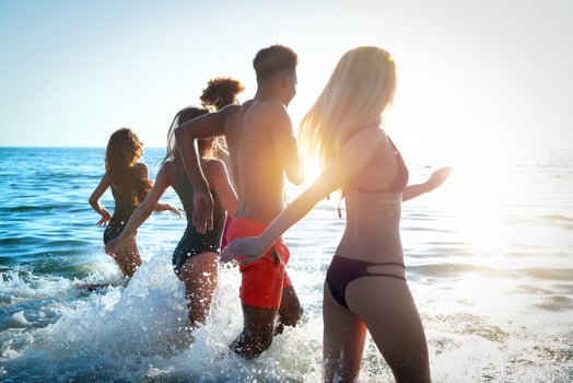 Group of friends run in the sea. Concept of summertime photo