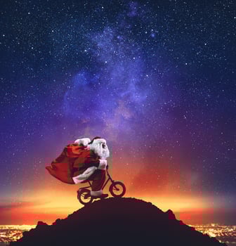 Santa Claus on a little bike on the peak of a mountain under the stars photo