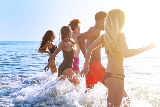 Group of friends run in the sea. Concept of summertime photo