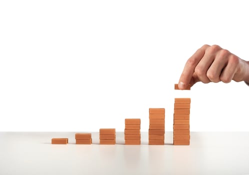 Businessman puts a brick on a bricks pile. Concept of growing statistics and success photo