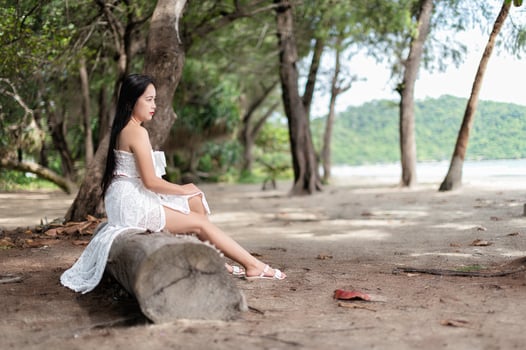 A woman in a white dress sitting on a log photo