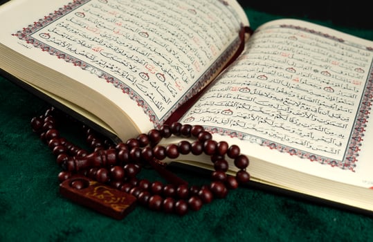 The open Quran book and rosary for religion background photo