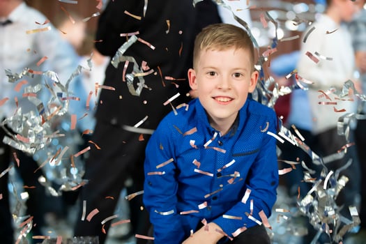Happy little boy in confetti.Magic time - Portrait of a very happy child with hands smiling while falling confetti. At a children's party. photo