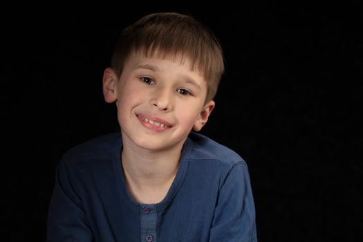 Portrait of a ten-year-old boy on a dark background. The child looks into the camera with intelligent eyes. Handsome boy of school age. photo
