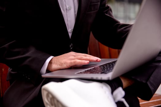 Young guy in a suit works on a computer in the park, hands on a plan photo