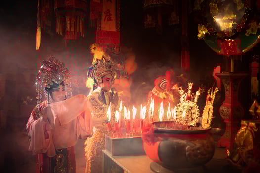 Male and female Chinese opera actors Light a candle to pray homage to the gods to enhance the prosperity for yourself on the occasion photo