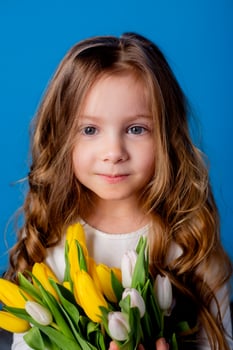 portrait of a charming smiling little girl with a bouquet of tulips in her hands. lifestyle. fresh flowers. International Women's Day. space for text. High quality photo