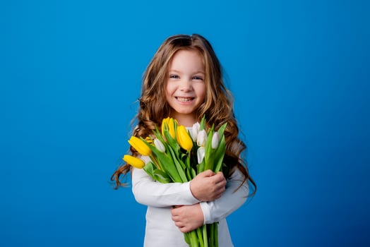 portrait of a charming smiling little girl with a bouquet of tulips in her hands. lifestyle. fresh flowers. International Women's Day. space for text. High quality photo