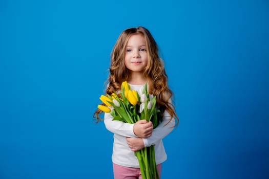 portrait of a charming smiling little girl with a bouquet of tulips in her hands. lifestyle. fresh flowers. International Women's Day. space for text. High quality photo
