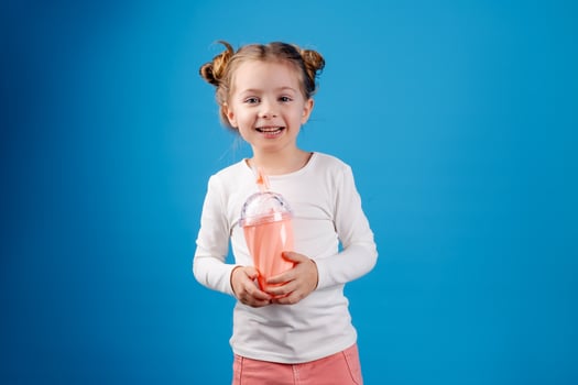 portrait of a small happy girl of Slavic appearance drinking a cocktail of berries. place for text photo