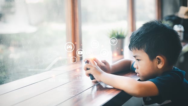 Handsome Asian man sits at home by a glass window with a mobile phone at home. Using various media with great enthusiasm serious look. Online education, Homeschooling. photo