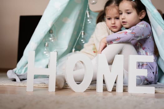 Two girls sisters at wigwam tent with wooden home letters. photo