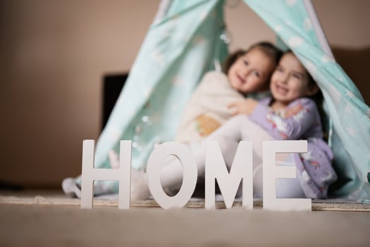 Two girls sisters at wigwam tent with wooden home letters. photo
