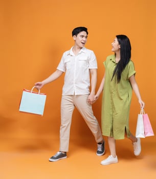 Young Asian couple holding shopping bag on background photo