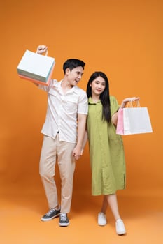 Young Asian couple holding shopping bag on background photo