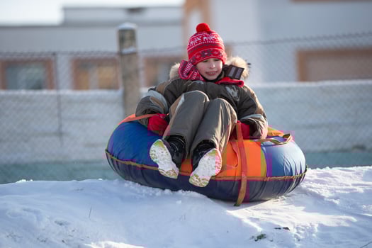 A happy boy up in the air on a tube sledding in the snow.. A boy slides down a hill in winter. photo